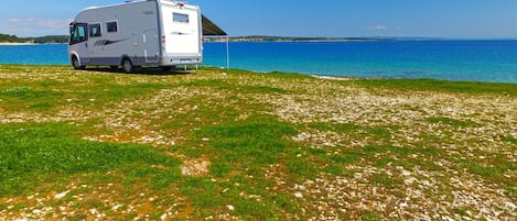 A white RV parked on a grassy area near a body of water.