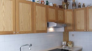 Une cuisine avec des meubles de rangement en bois, un évier en acier inoxydable et un plan de travail noir.