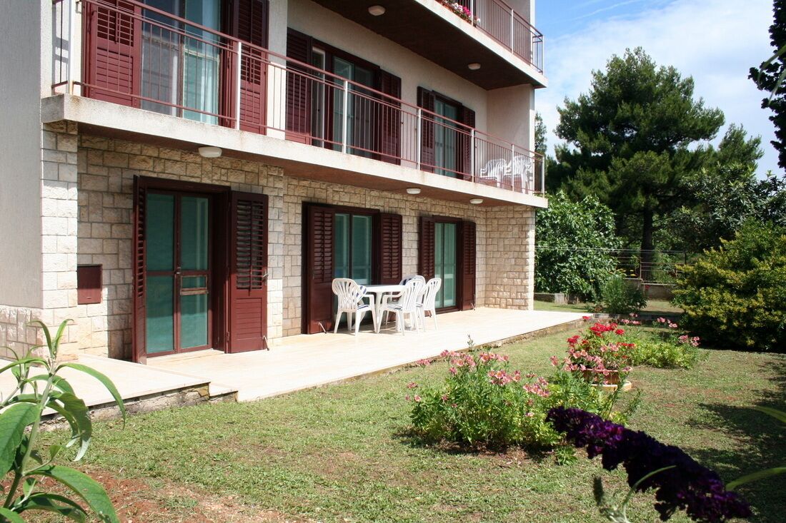 Un bâtiment à deux étages doté d’un balcon, d’un petit espace extérieur aménagé pour s’asseoir et d’un jardin bien entretenu.