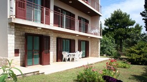 Un bâtiment à deux étages doté d’un balcon, d’un petit espace extérieur aménagé pour s’asseoir et d’un jardin bien entretenu.