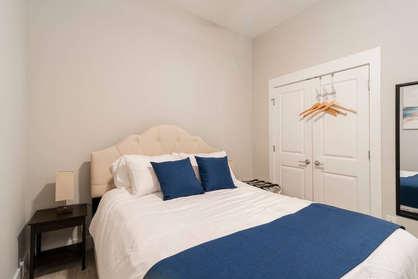 Una camera da letto con un letto, un comodino, una porta e un appendiabiti.