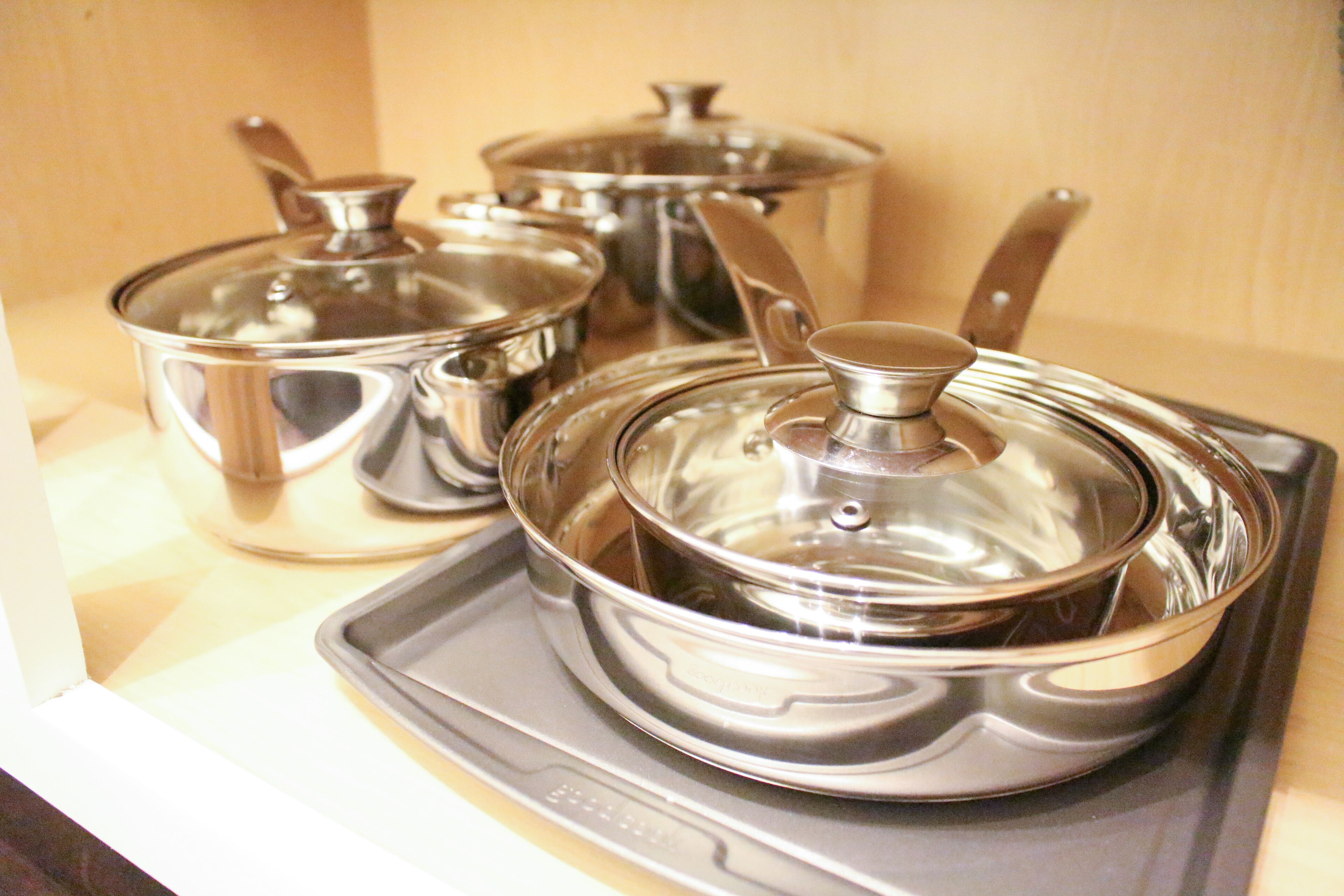 A set of stainless steel pots and pans on a tray.