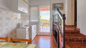 A compact kitchen with a dining area, a staircase, and a view of the outdoors.