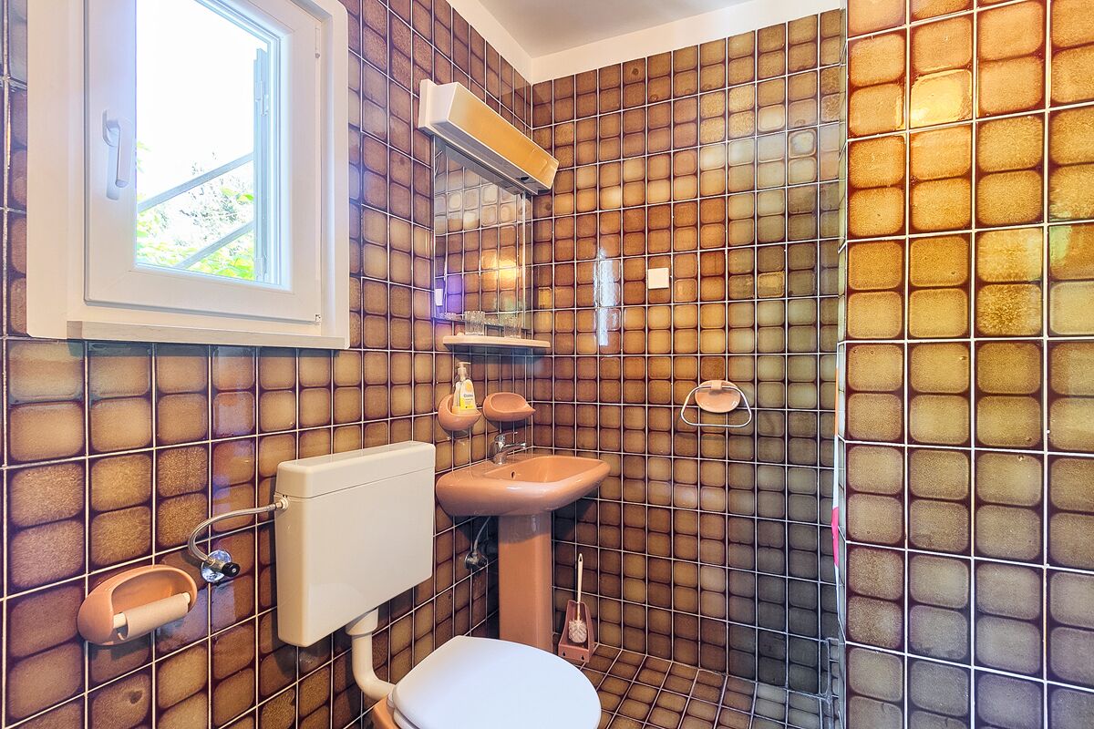 Un baño con inodoro, lavamanos y ventana.