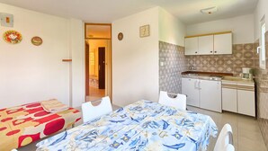 Ein kompaktes Hotelzimmer mit Bett, einem kleinen Tisch und einer Küchenzeile.