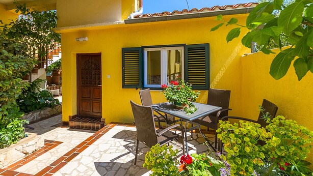 A yellow building with a tiled patio, a table with chairs, and potted plants. - Apartment 1220/17851 (Istria - Premantura), 500m from the beach (Premantura)