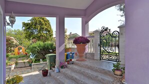 A covered outdoor area with steps leading to a gate, surrounded by potted plants and a small garden.