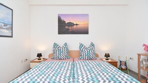 A bedroom with a bed, two nightstands, a lamp, a painting, and a small shelf with figurines. - Apartment 1223/11186 (Istria - Peroj), 900m from the beach (Peroj)