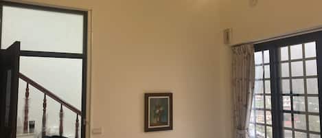 Un dormitorio con una cama, una ventana con cortinas, una puerta y una escalera.