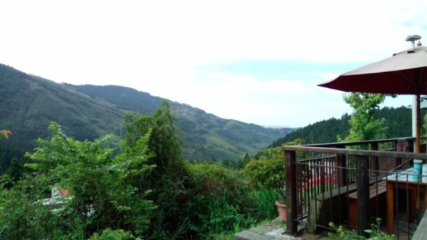 A wooden deck with a red umbrella, overlooking a mountainous landscape. - Jin Lan Homestay (Zhuqi)