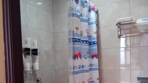 A bathroom with a shower curtain featuring a train theme, a toilet, and a sink. - Jin Lan Homestay (Zhuqi)