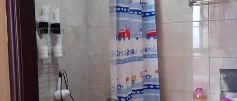 Un baño con cortina de ducha temática de tren, un inodoro y un lavamanos.