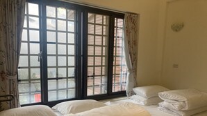 A hotel room with two beds, a large window with curtains, and a view of the outside. - Jin Lan Homestay (Zhuqi)