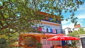 A two-story building with a red umbrella, outdoor seating, and a stone archway. - Apartment 1224/11230 (Istria - Premantura), 300m from the beach (Premantura)