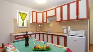 A compact kitchen with wooden cabinets, a gas stove, a sink, and a refrigerator. - Apartment 1227/11310 (Istria - Premantura), 300m from the beach (Premantura)