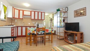 A compact living space with a kitchenette, a dining area with a table and chairs, a television, and a bed. - Apartment 1227/11310 (Istria - Premantura), 300m from the beach (Premantura)