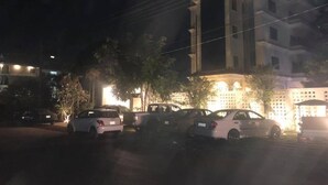 Un estacionamiento con varios coches aparcados frente a un edificio con ventanas iluminadas.
