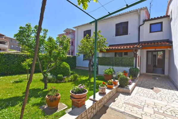 Un immeuble résidentiel doté d’un jardin, de plantes en pot et d’une terrasse carrelée.