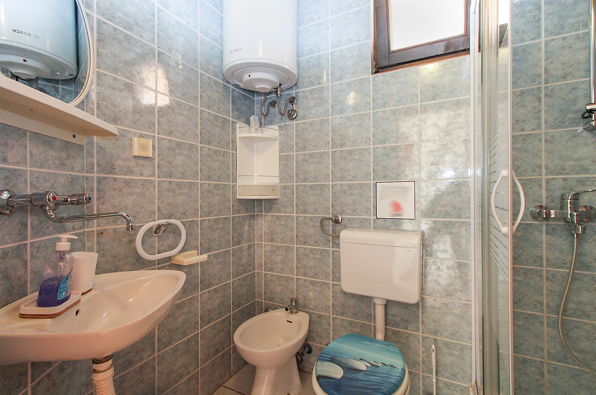 A bathroom with a sink, bidet, toilet, and shower.