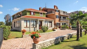 Une maison à deux étages avec une façade en briques, de grandes fenêtres et une allée pavée.
