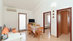 A dining area with a table, chairs, and a television. There is a door leading to another room and a wall-mounted air conditioner. - Apartment 1249/11901 (Istria - Valbandon), 500m from the beach (Valbandon)