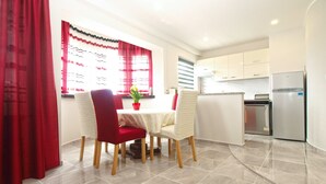 A modern kitchen with white cabinets, a stainless steel refrigerator, and a dining area with a table and chairs. - Apartment 1251/11917 (Istria - Fažana), 350m from the beach (Fažana)