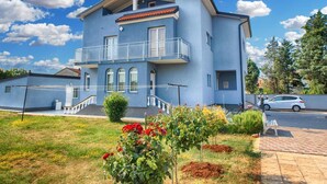 A two-story building with a balcony, a small garden with flowers, and a parked car in the driveway. - Apartment 1251/11917 (Istria - Fažana), 350m from the beach (Fažana)