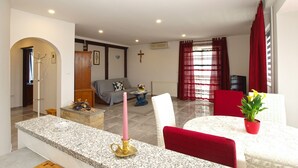 A living room with a granite countertop, a red chair, a white chair, a small table with a potted plant, and a television. - Apartment 1251/11917 (Istria - Fažana), 350m from the beach (Fažana)
