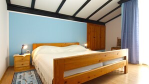 Ein Schlafzimmer mit einem hölzernen Bett, Nachttischen, einem Kleiderschrank und einer blauen Wand.