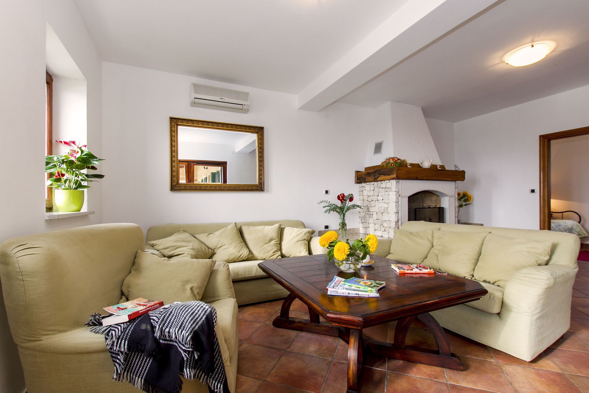 Una sala de estar con dos sofás color beige, una mesa de centro de madera, un espejo y una chimenea.