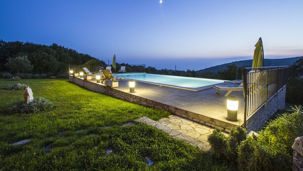 A pool area with lounge chairs and a stone deck, surrounded by grass and trees, under a twilight sky. - Villa 1254/11990 (Istria - Skitača), 5000m from the beach (Skitača)