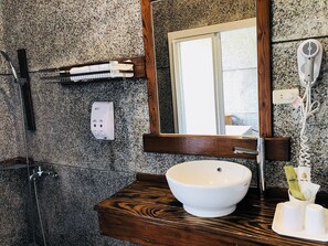 A bathroom with a wooden vanity, a white sink, a mirror, a towel rack, a hairdryer, and a shower. - Yingjia Hot Spring Homestay (Luye)