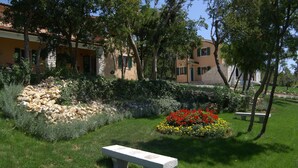 A garden with a stone wall, a bench, and a flower bed with red and yellow flowers. - Apartment 1255/12014 (Istria - Koromačno), 4000m from the beach (Koromačno)