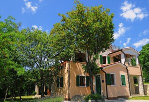 A two-story building with a stone facade, green shutters, and a satellite dish.