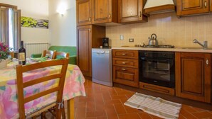 A kitchen with wooden cabinets, a stove, a dishwasher, and a table with chairs. - Borgo Fontana by Interhome (Vinci)