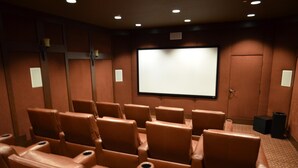 En biograf med lädersäten, en stor filmduk och ett mattbeklätt golv.