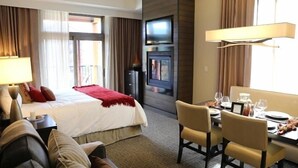 Ett hotellrum med en säng, ett skrivbord med stolar, en tv och en öppen spis.
