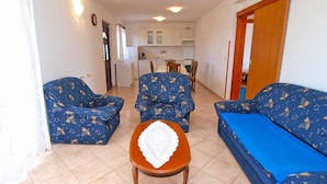 A living room with two blue patterned sofas, a wooden coffee table, and a kitchen in the background.