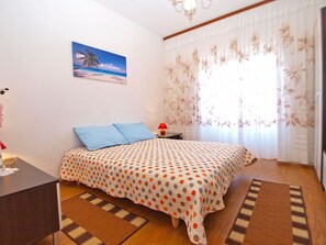 A bedroom with a bed, a desk, a chair, a lamp, and a window with curtains.