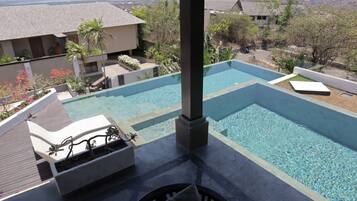 A pool area with lounge chairs and a view of the surrounding landscape.