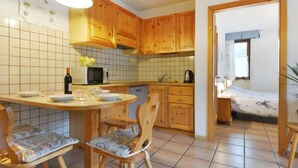 Una cucina compatta con mobili in legno, un forno a microonde e un'area pranzo con due sedie.