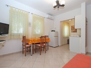 A compact living space with a dining area, kitchenette, and a TV.