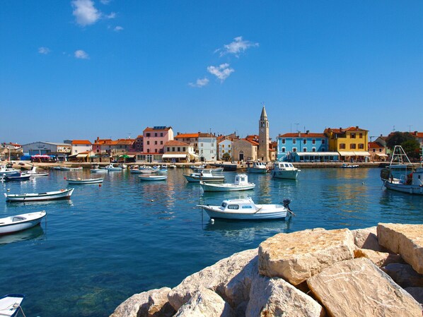 Enjoy a serene waterfront scene with boats docked in calm waters, surrounded by natural rocks and historic architecture.