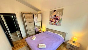 Un dormitorio con cama, mesita de noche, armario, espejo y un cuadro en la pared.
