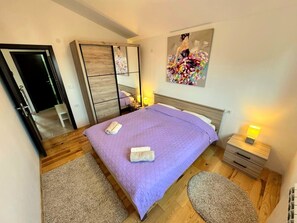 Ein Schlafzimmer mit Bett, Nachttisch, Kleiderschrank, Spiegel und einem Bild an der Wand.