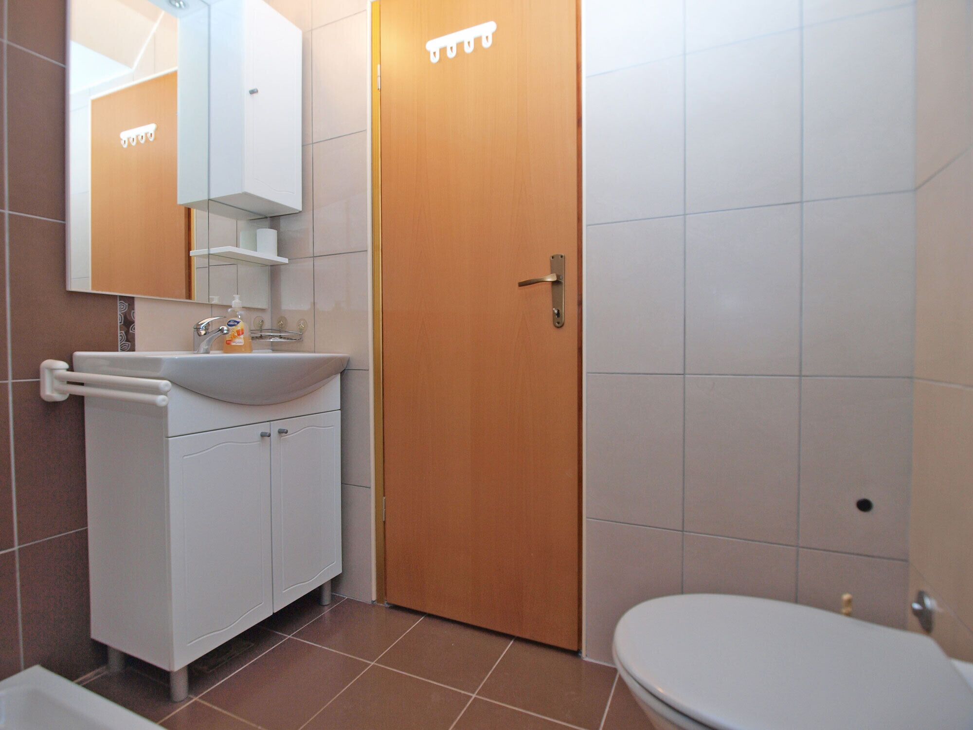 A bathroom with a white sink, mirror, and toilet.