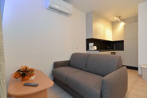 Relax in this cozy living space with a sofa, side table, and kitchen.