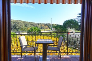 Enjoy the serene view from this balcony, featuring two comfortable chairs and a small table.