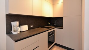 A compact kitchen with a coffee maker, toaster, and a sink.