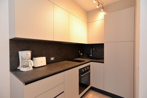 Enjoy cooking in this well-equipped kitchen with oven, coffee maker, and sleek cabinetry.